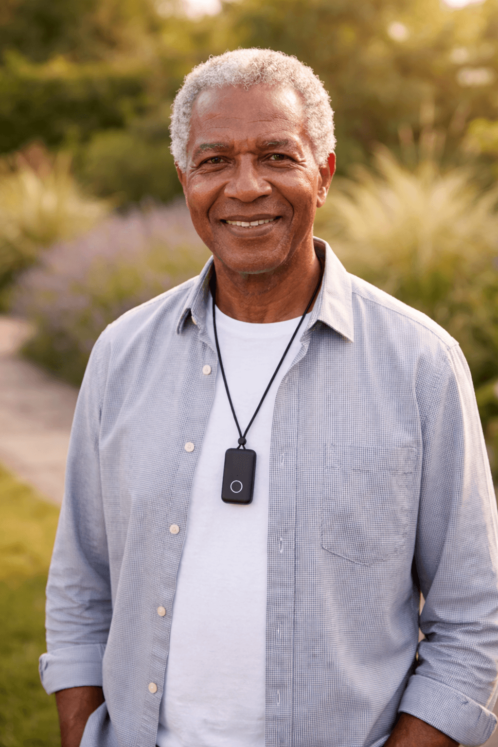 Indy Mobile portable GPS medical alert clipped to a senior woman's belt while walking through a sunny park